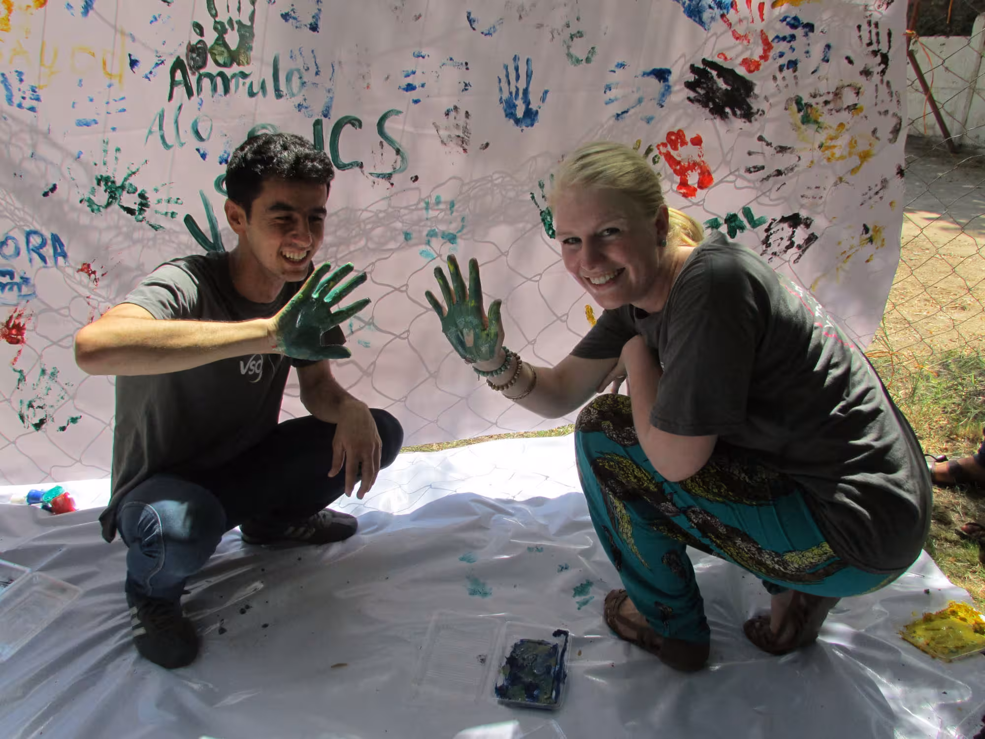 Photo of two people painting a canvas with their hands