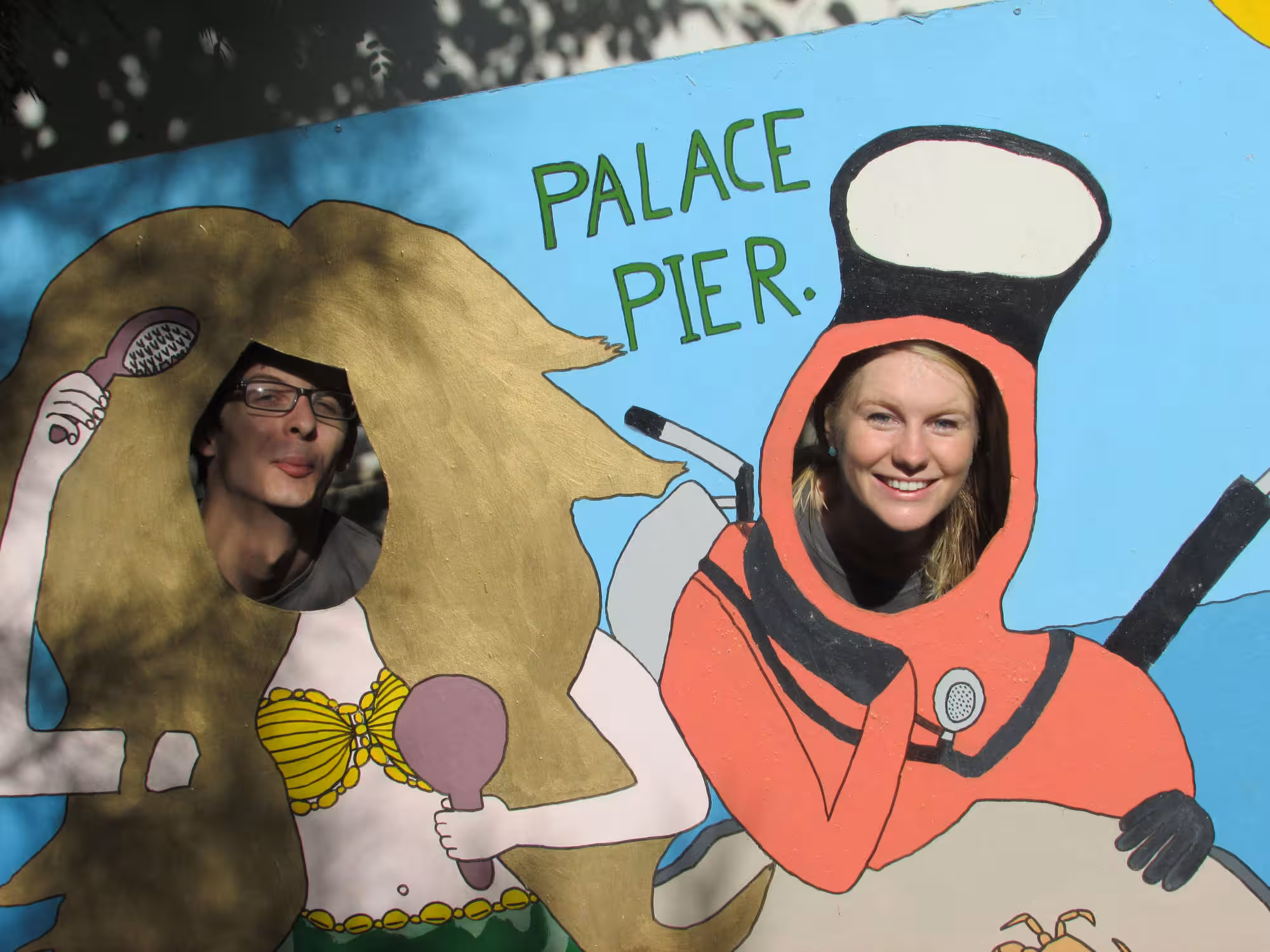 Photo of two volunteers posing behind a photo cutout board